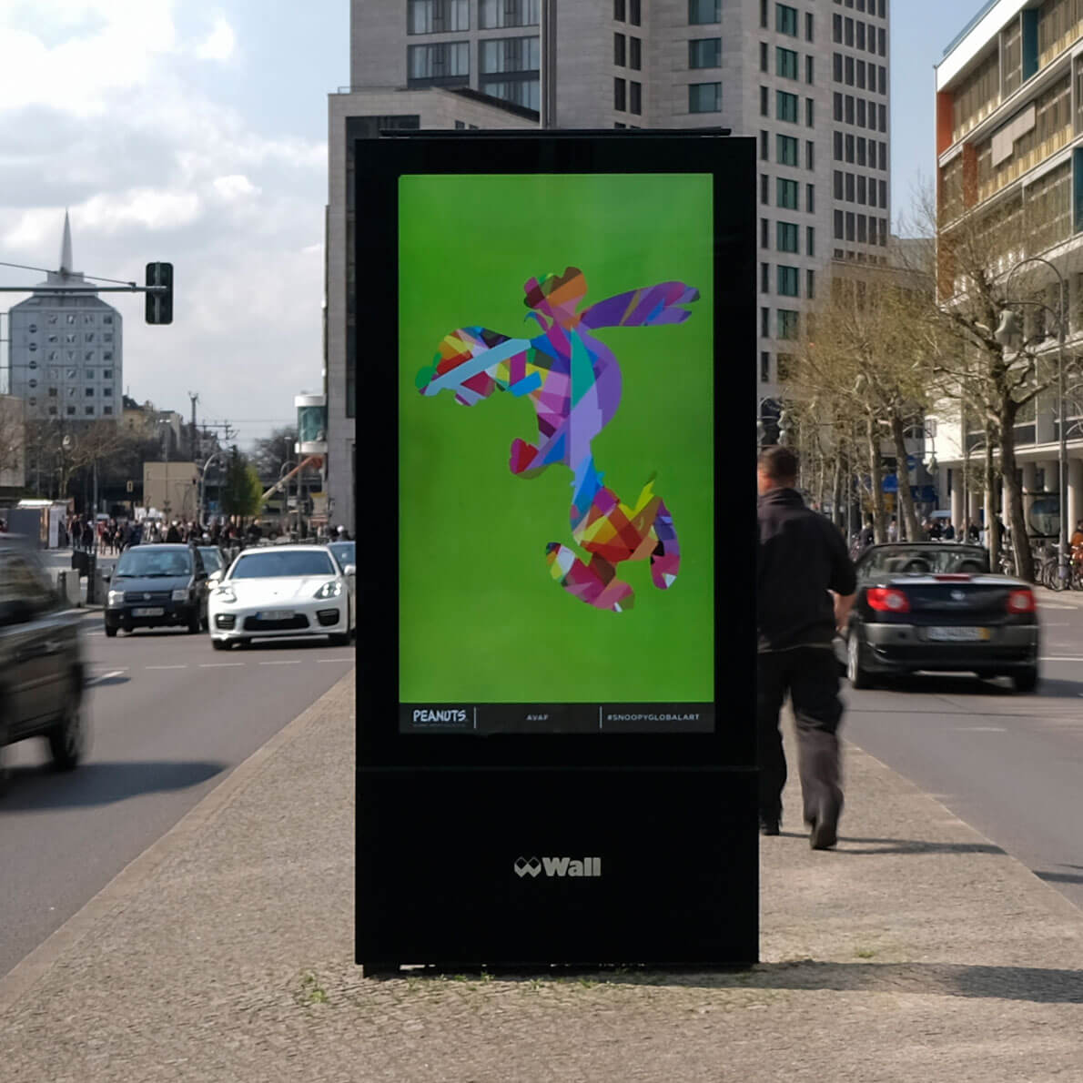 A large LED display showcasing a colourful image on a sidewalk in a busy city.
