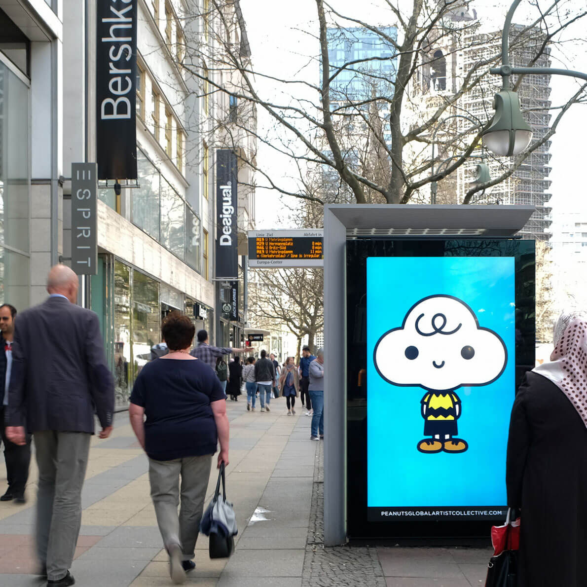 People walking on a busy street, passing by a large LED display 