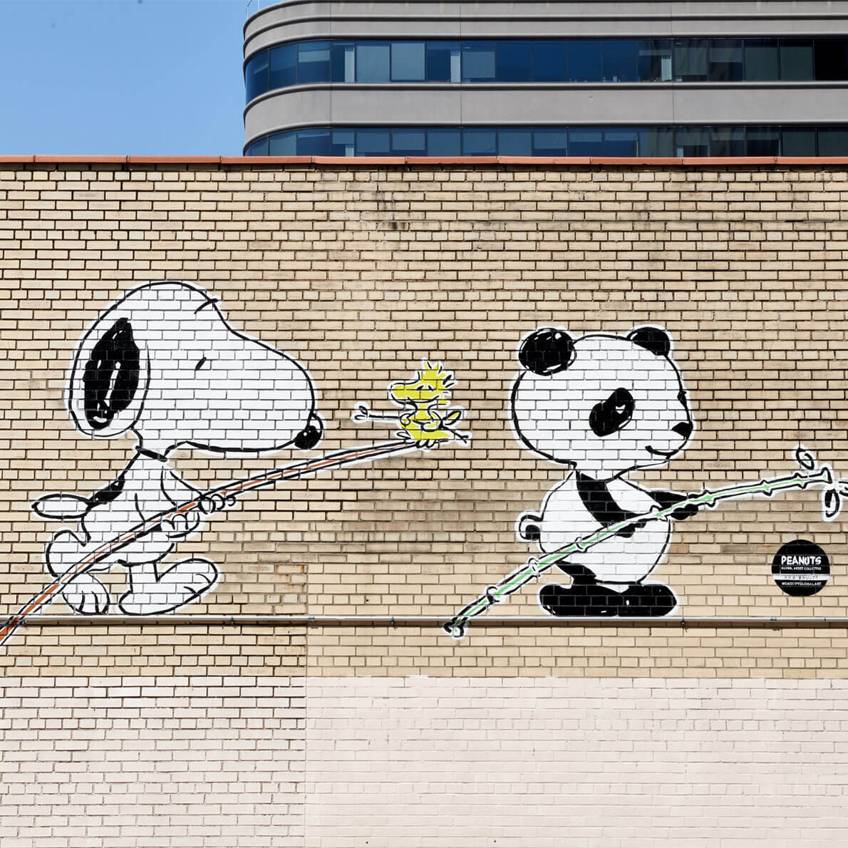 A mural of a black and white dog and a panda on a brick wall.