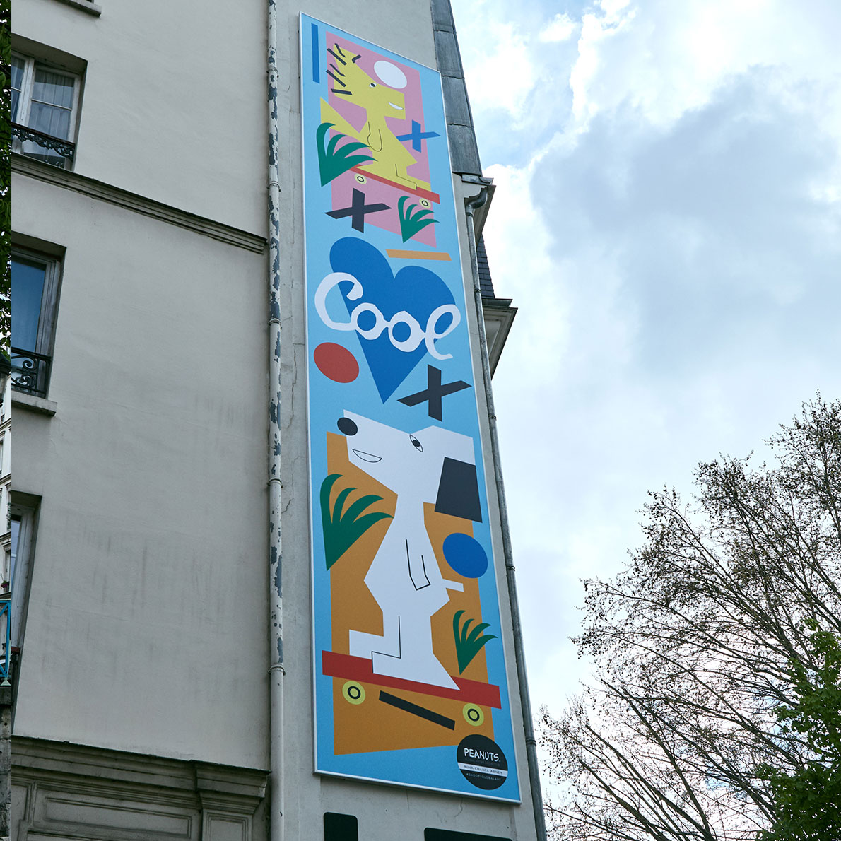 A close-up of colourful mural on the side of a white brick building.