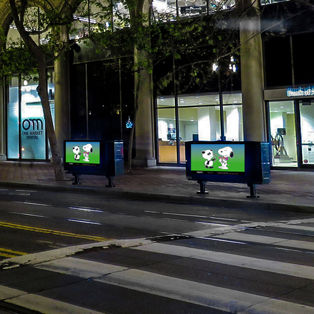 A street crossing at night and two rectangular objects on the sidewalk, displaying cartoon illustrations.