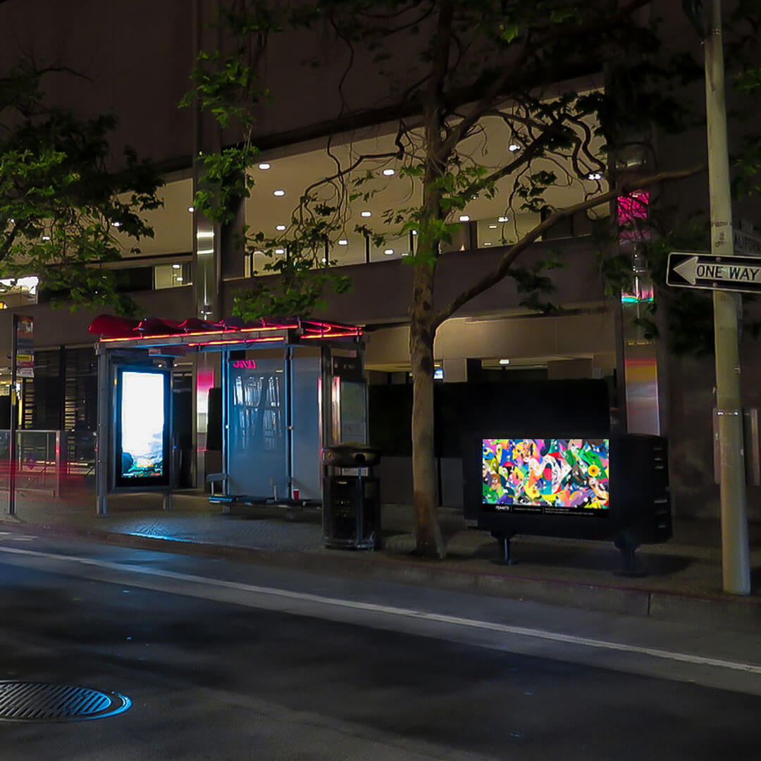 A colourful piece of art on display beside a glass bus shelter.