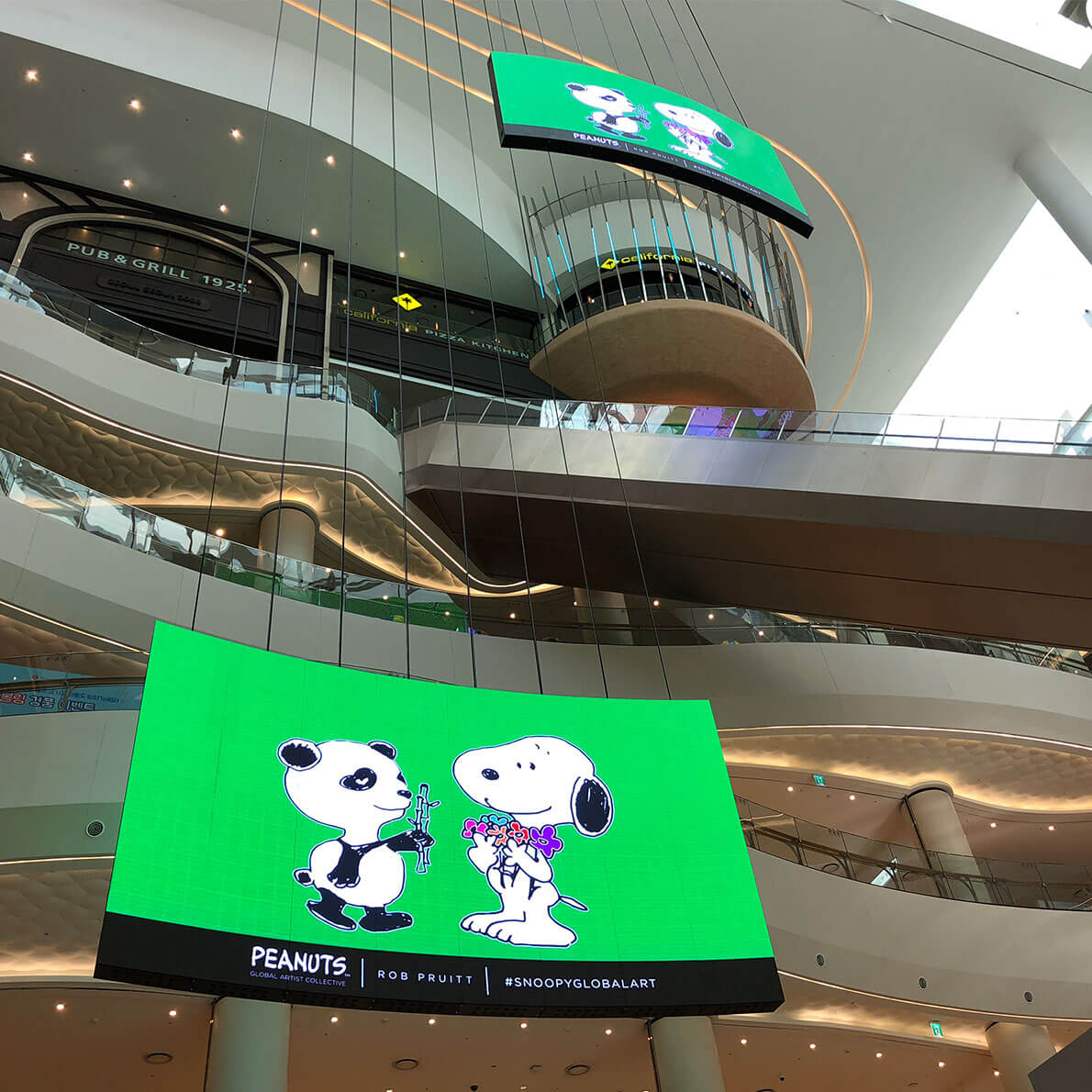 Two large LED screens hanging in a shopping mall.
