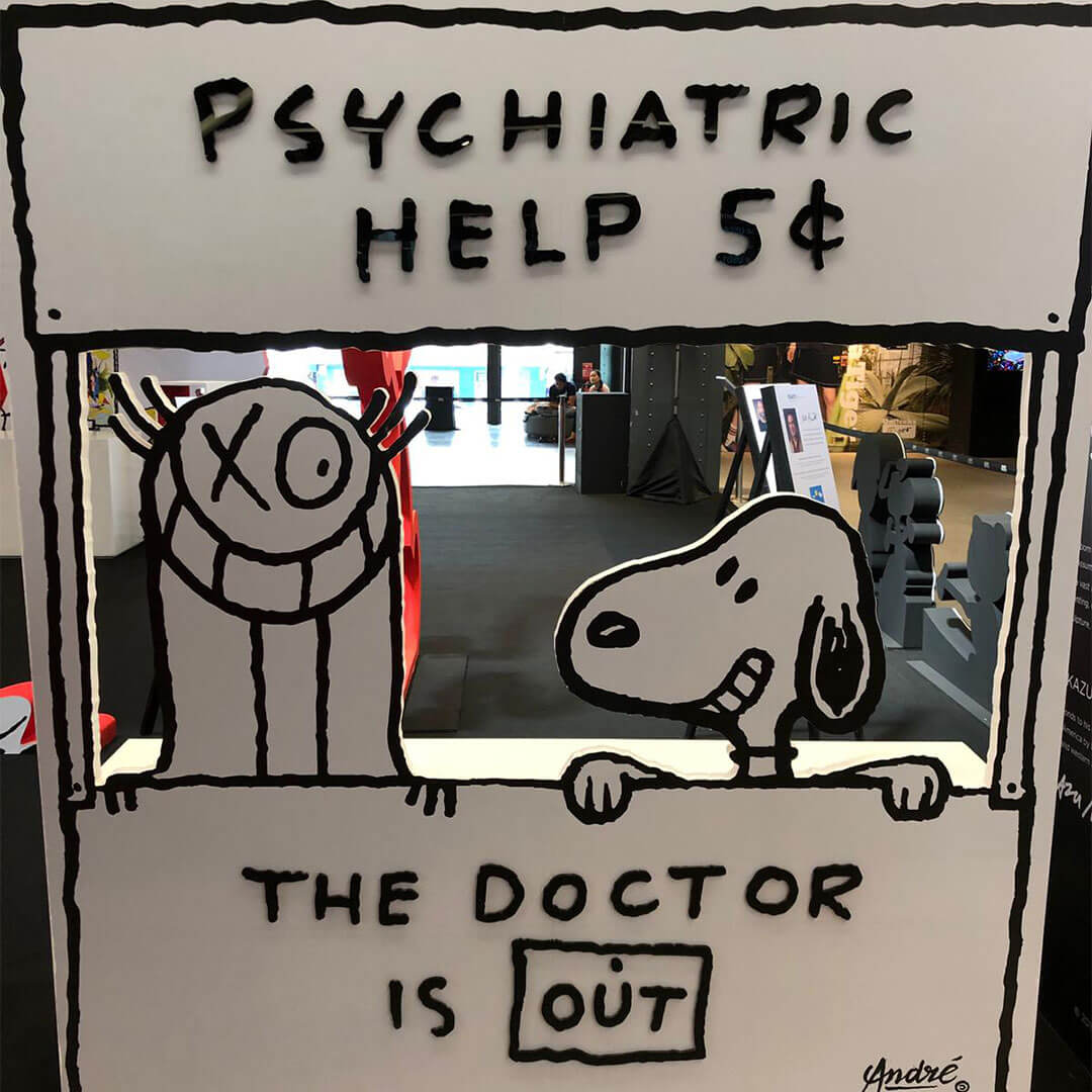 A black and white dog standing behind a stand which says: Psychiatric Help.