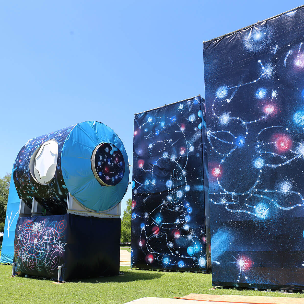 Three large, spray painted structures in a park.