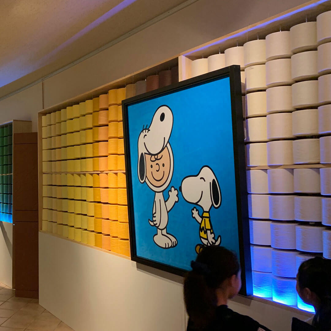 A TV hanging on a wall displaying a black and white dog and a boy wearing a dog costume.