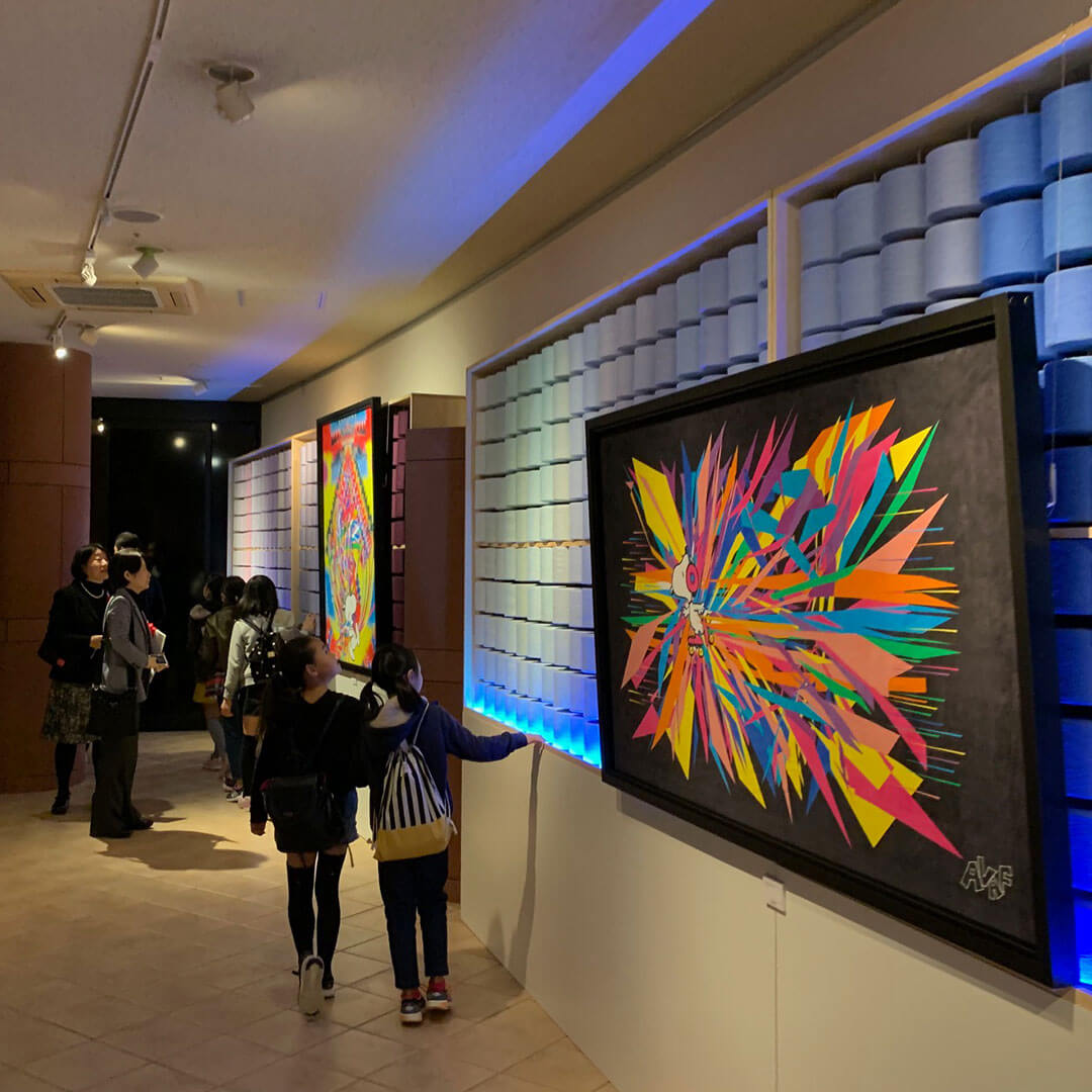 People standing in front of two large, colourful paintings in an indoor space.