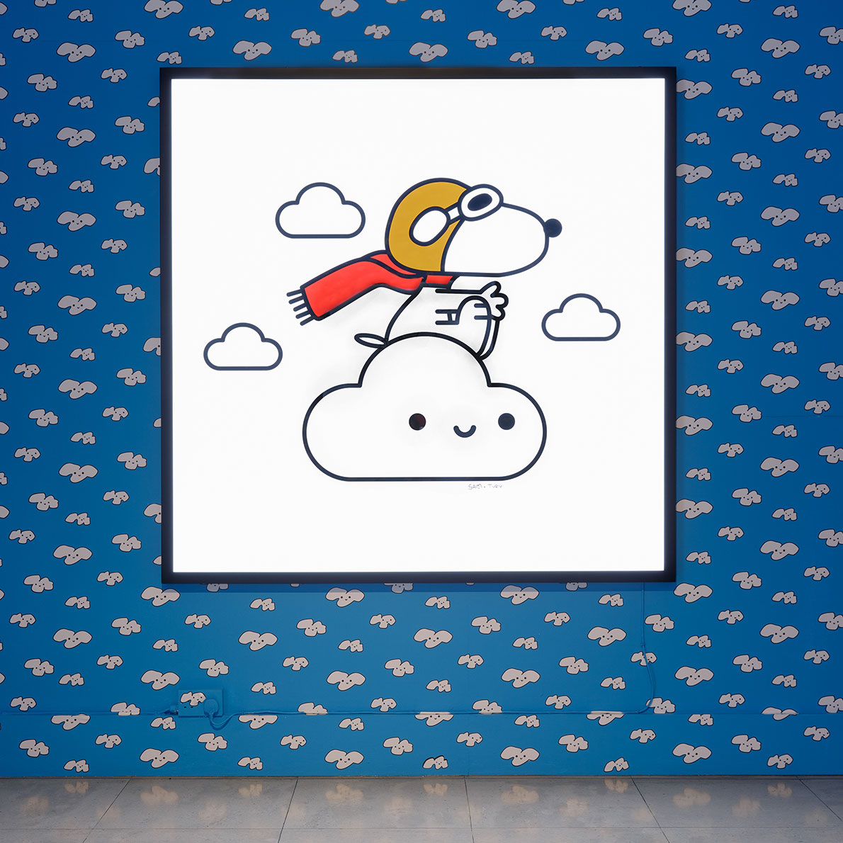An illustration of a black and white dog on top of a white cloud hanging on a blue wall.