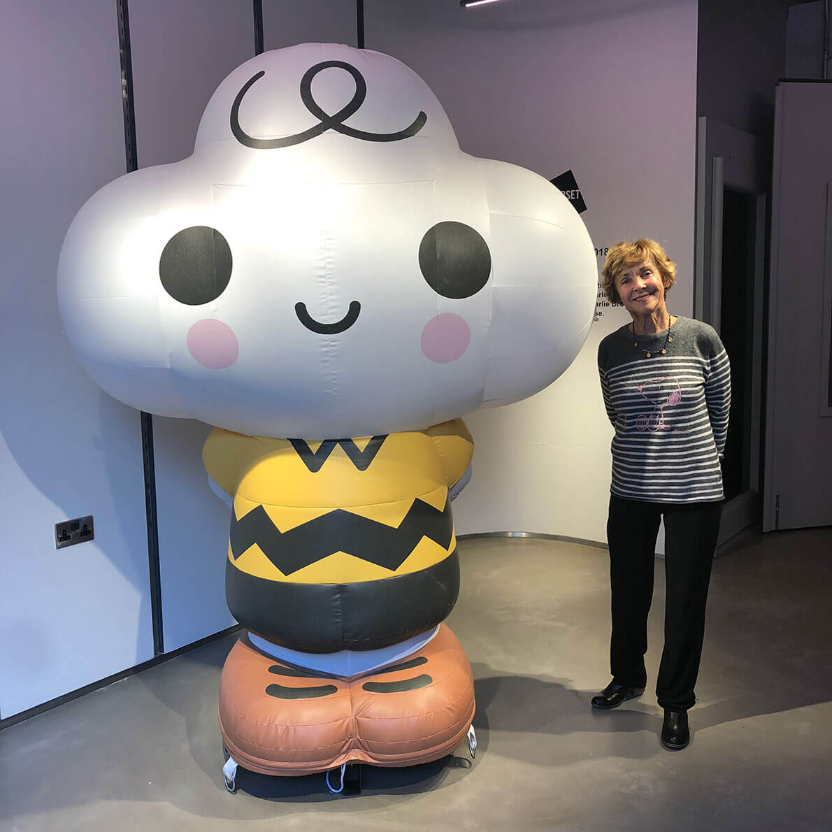 A woman standing beside a blow-up statue of a cartoon character.