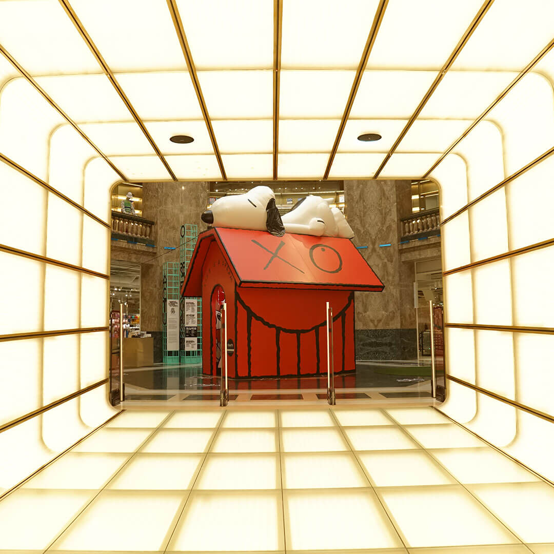 A red house and a black and white dog sleeping on the roof on display inside of a building.