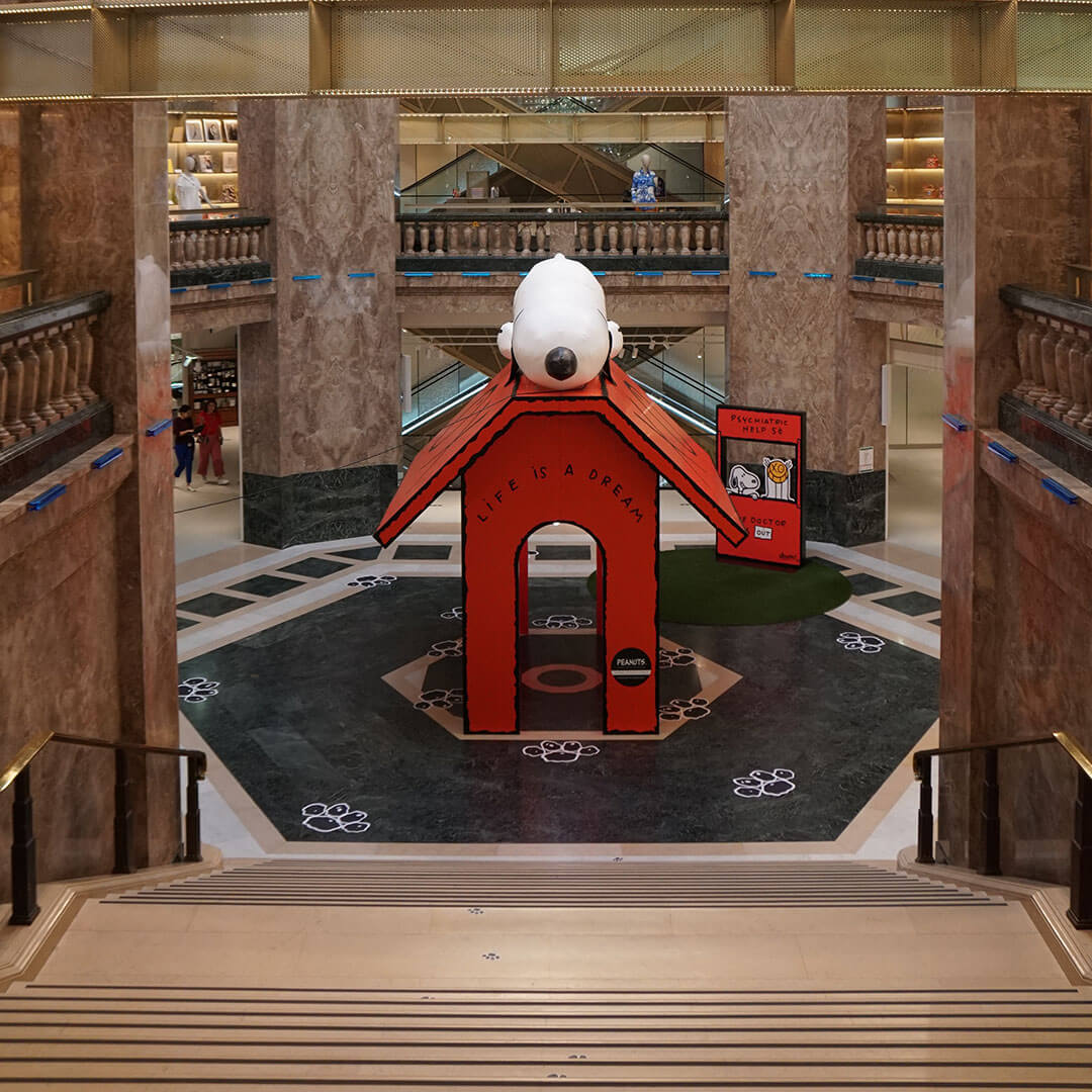 A red house and a black and white dog sleeping on the roof on display inside of a building.