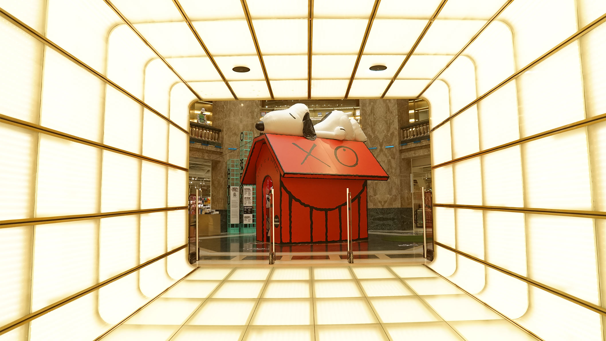 A red house and a black and white dog sleeping on the roof on display inside of a building