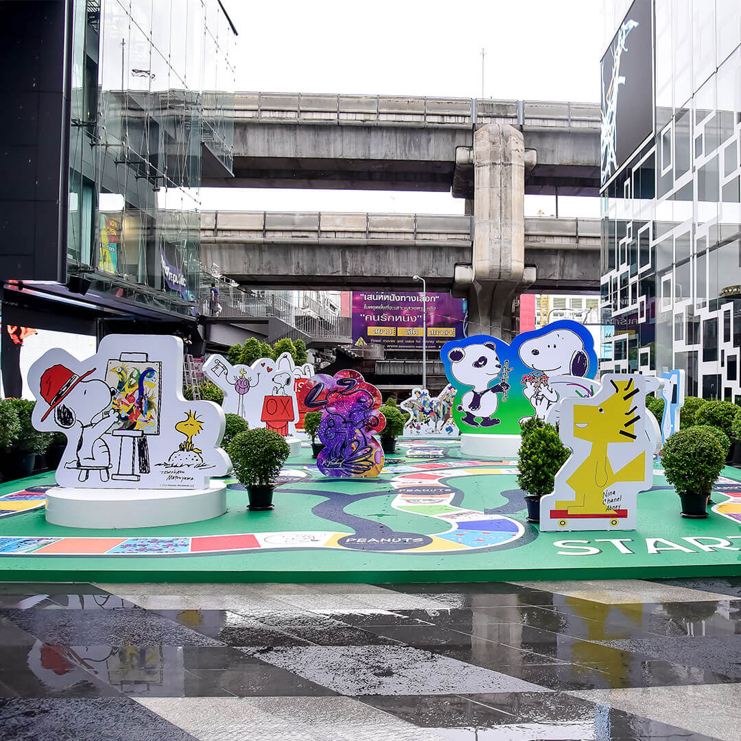 Colourful art installations outside in front of a bridge.