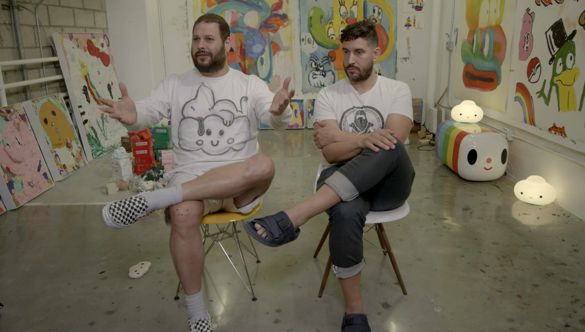 Two men sitting in chairs in an art studio having an interview. 