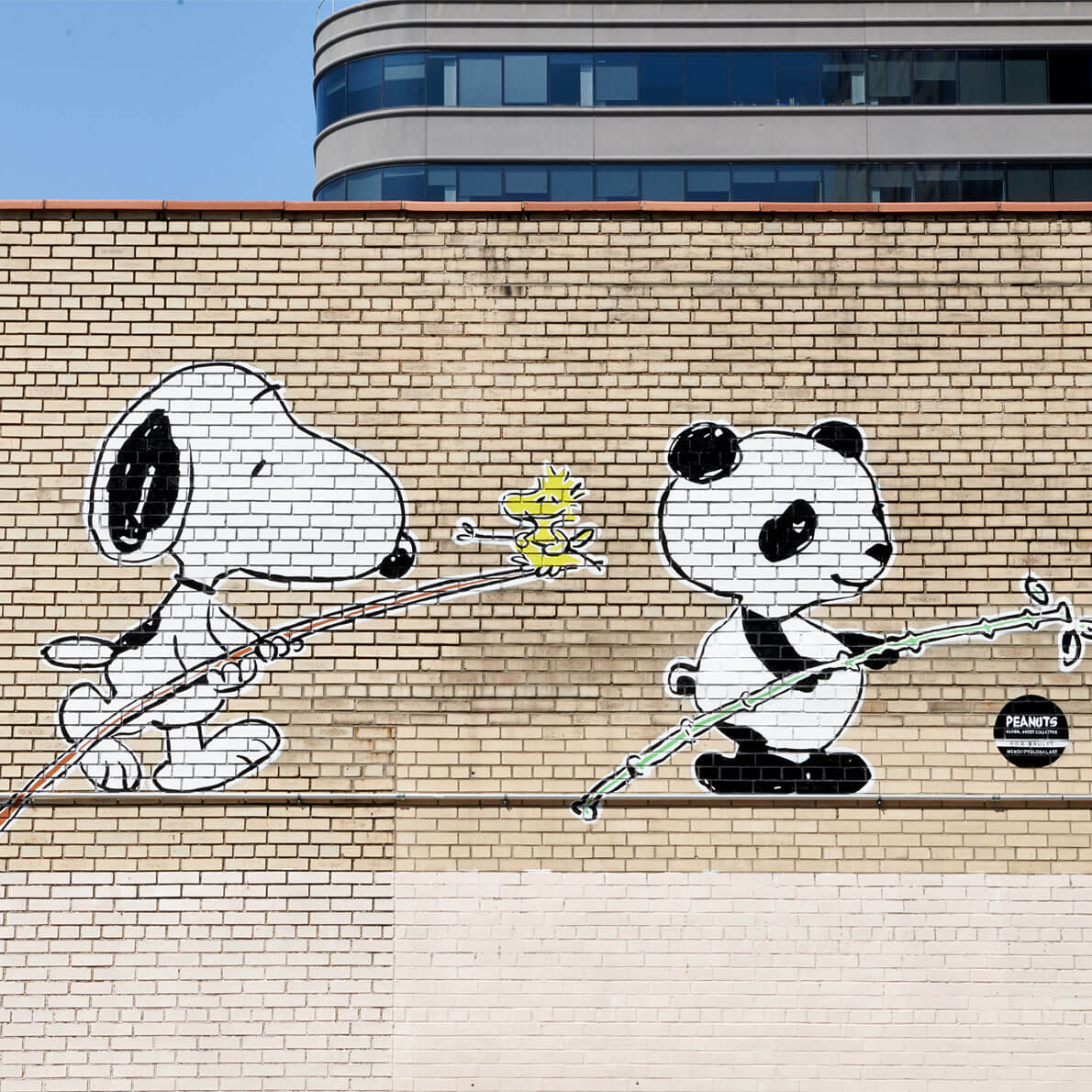 A mural of a black and white dog and a panda on a brick wall. 