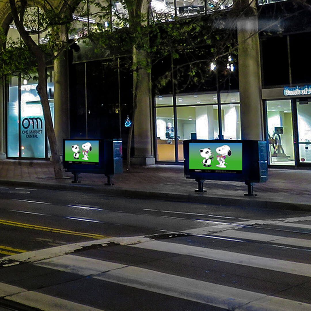 A street crossing at night and two rectangular objects on the sidewalk, displaying cartoon illustrations. 