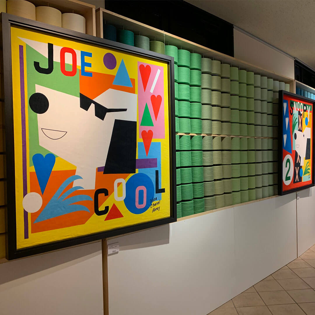 Two pieces of art hanging on a wall showcasing a black and white dog on a bright, multi-coloured background. 